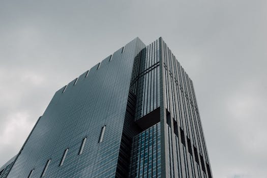 A contemporary skyscraper with a glass facade set against a gloomy sky, shot from a low angle.